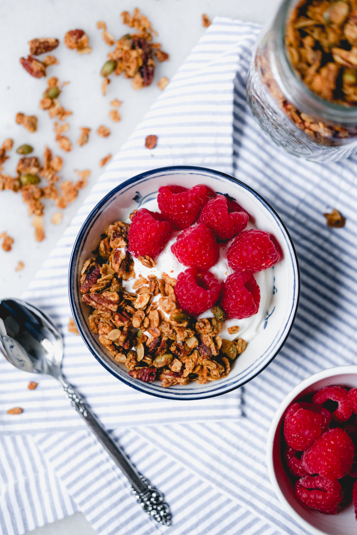 honey peanut butter granola in a small bowl with yogurt and raspberries