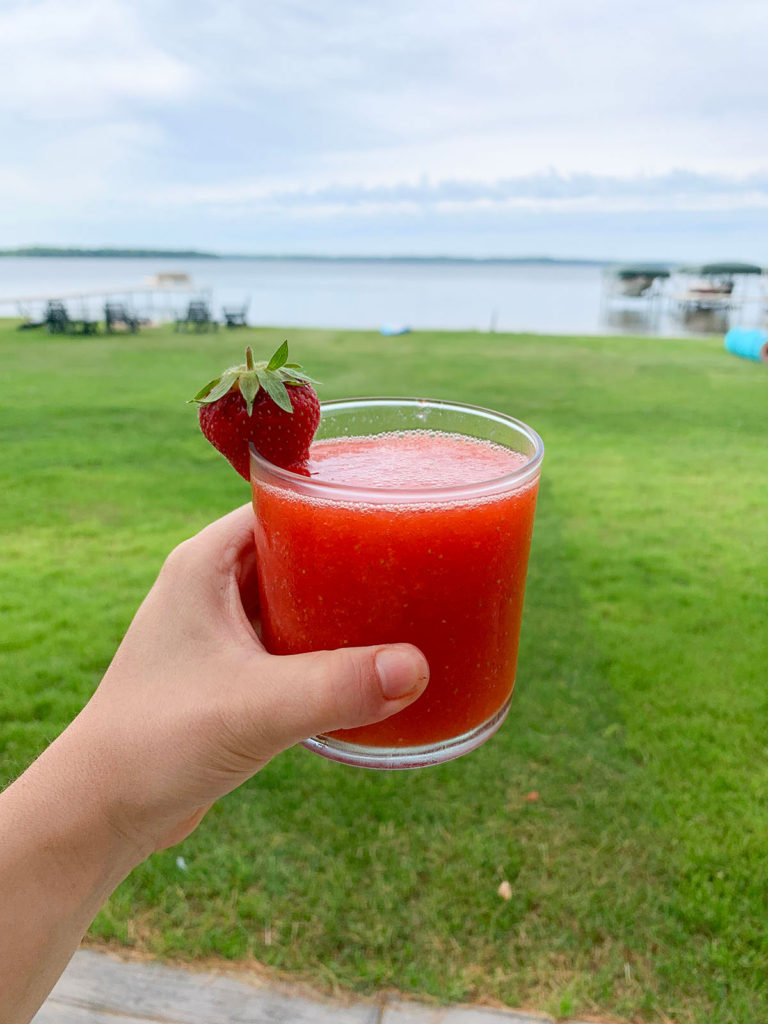 holding a frozen strawberry margarita at the lake
