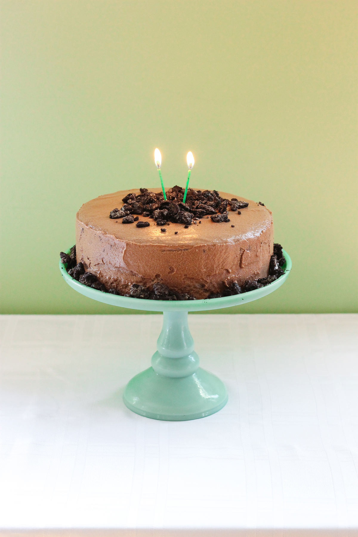 Mocha cake with mocha frosting with candles on a green cake platter