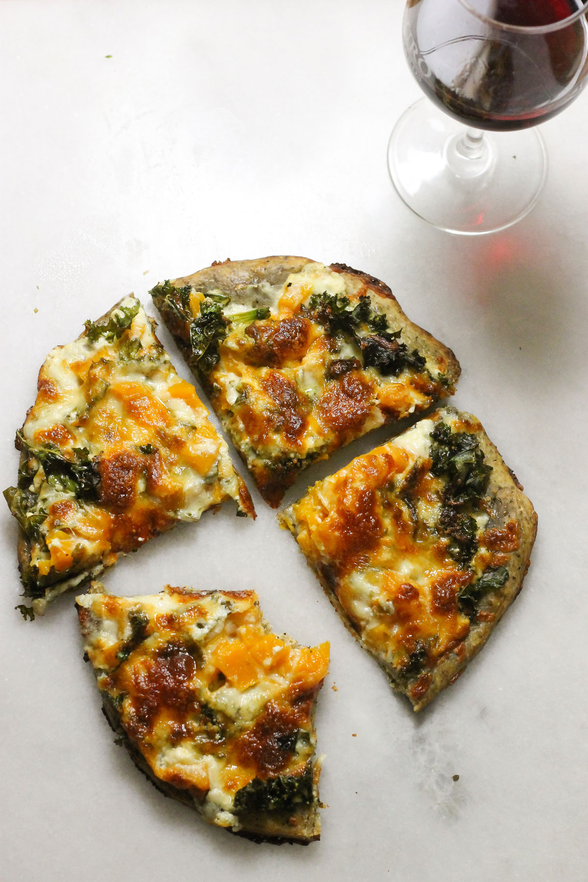 Butternut squash kale pizza with a glass of wine