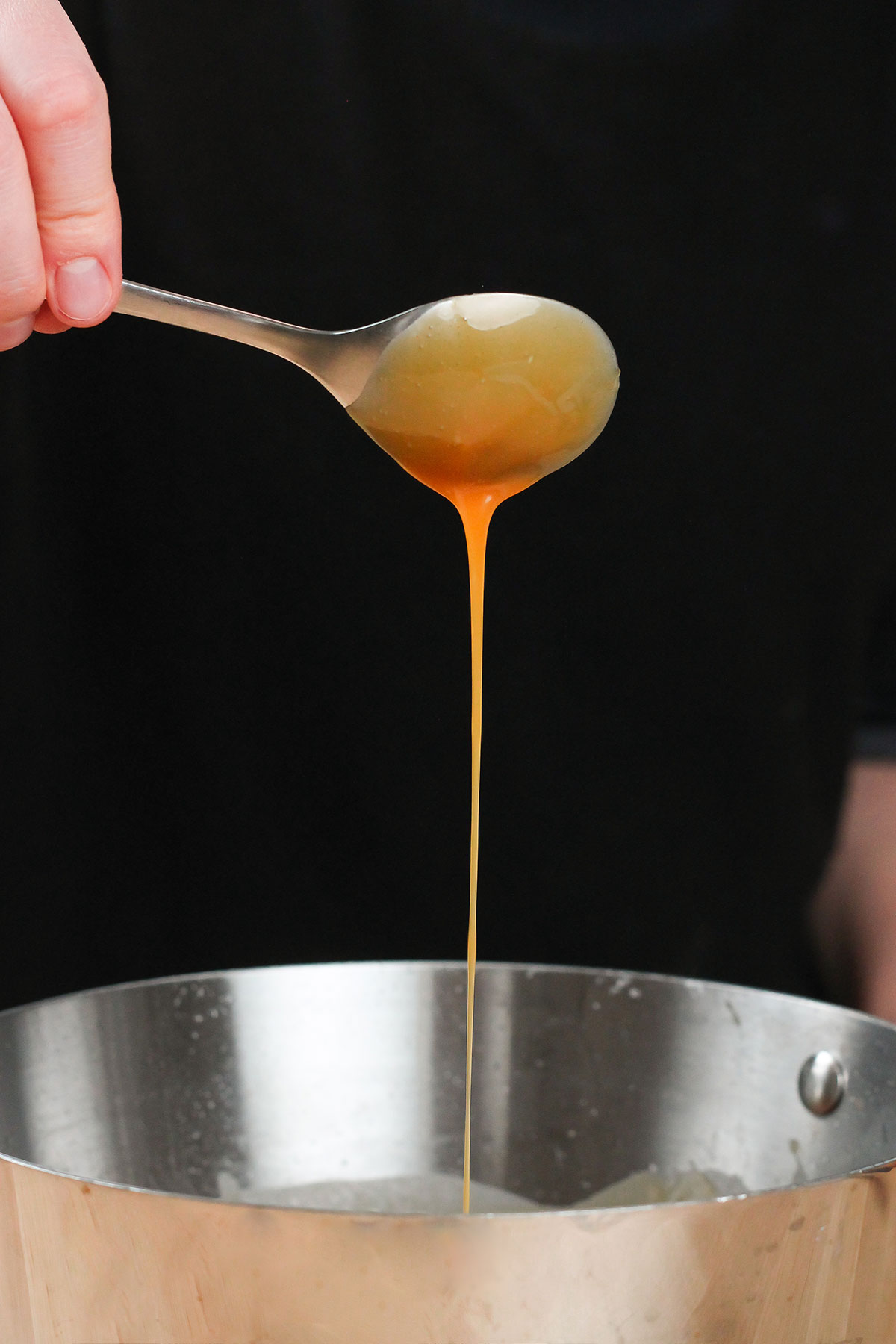 spoonful of caramel sauce dripping into pot