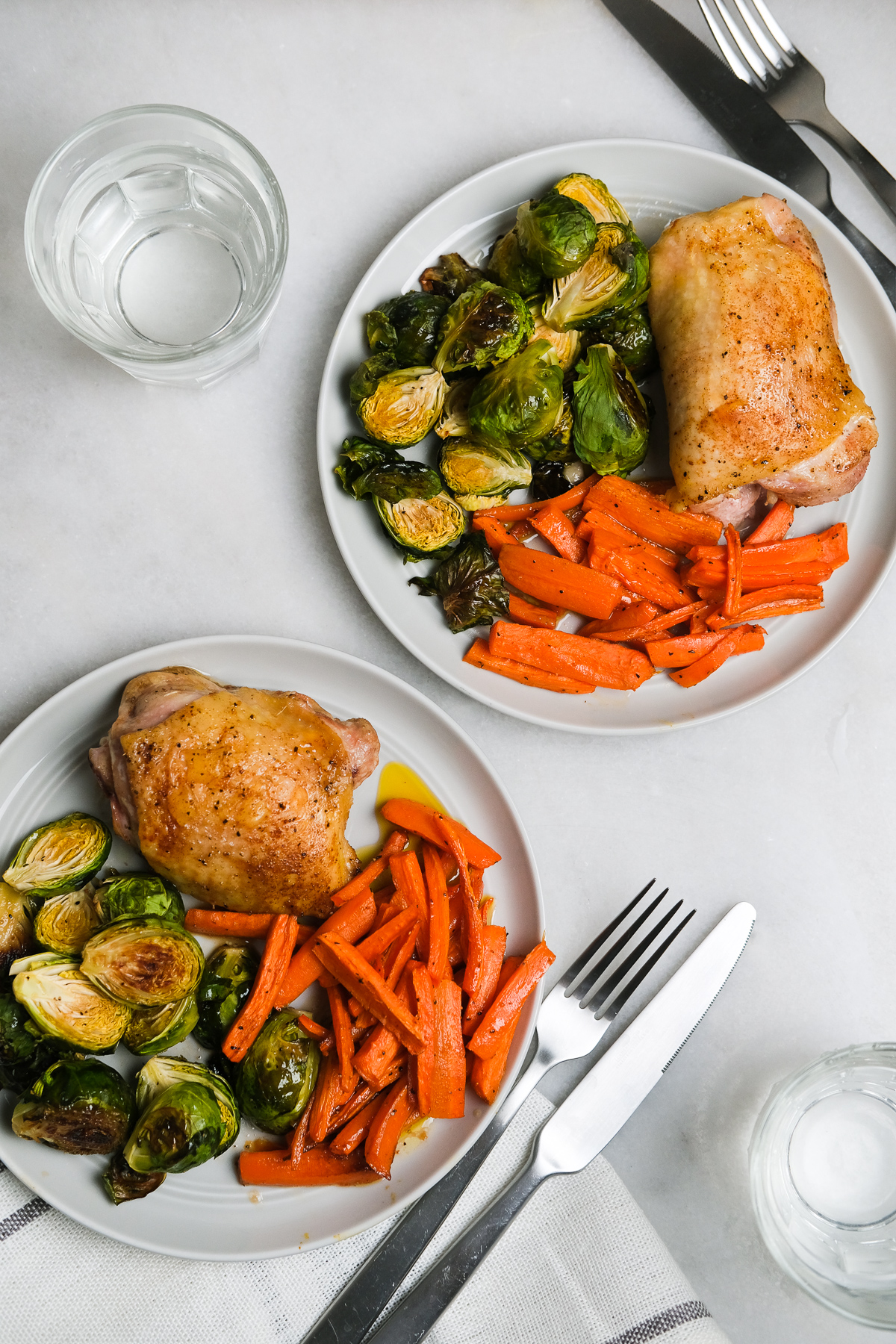 chicken thighs with roasted vegetables on plates ready to eat
