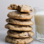 chocolate chip cookies piled up next to milk
