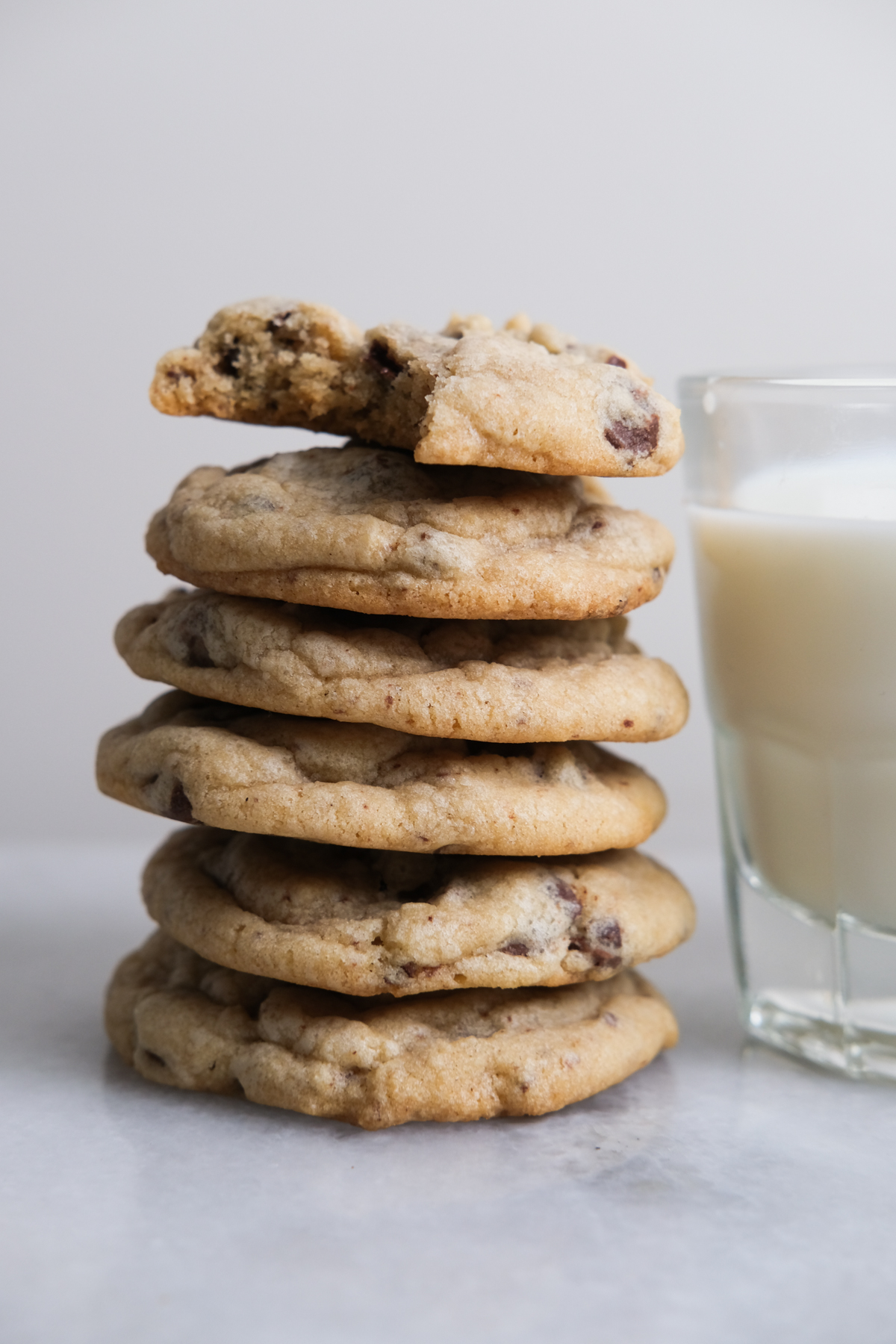 chocolate chip cookies piled up next to milk