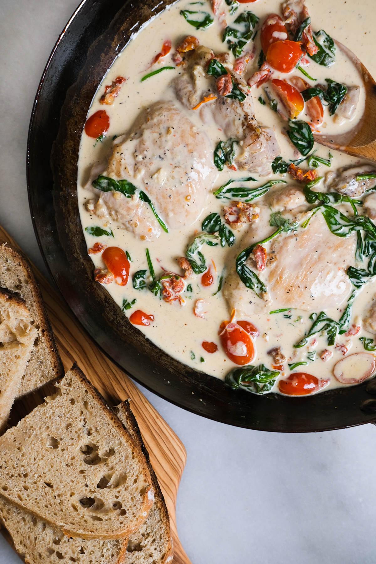 creamy tuscan in a pan with bread