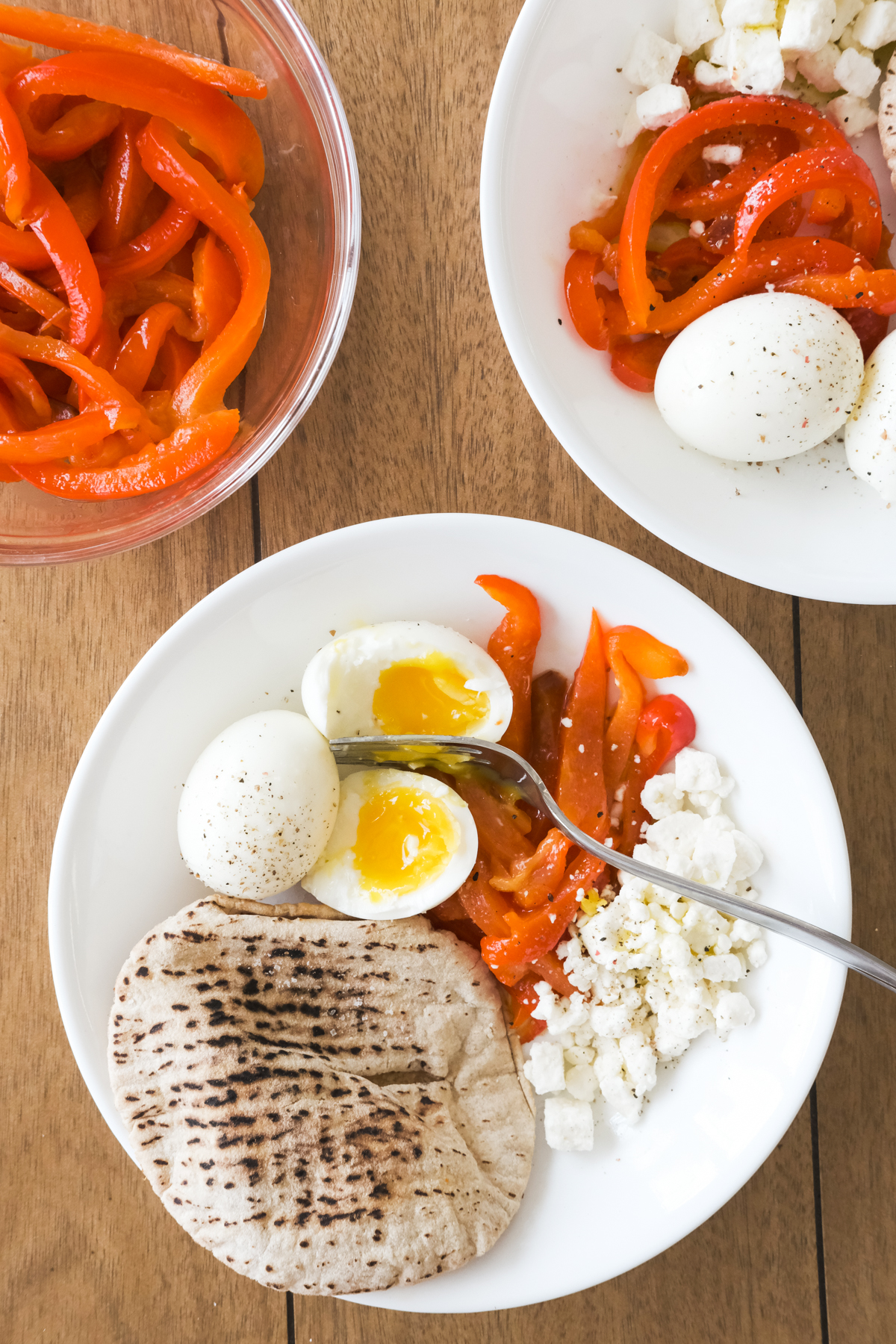 roasted red peppers in a bowl with soft boiled eggs cheese and pita