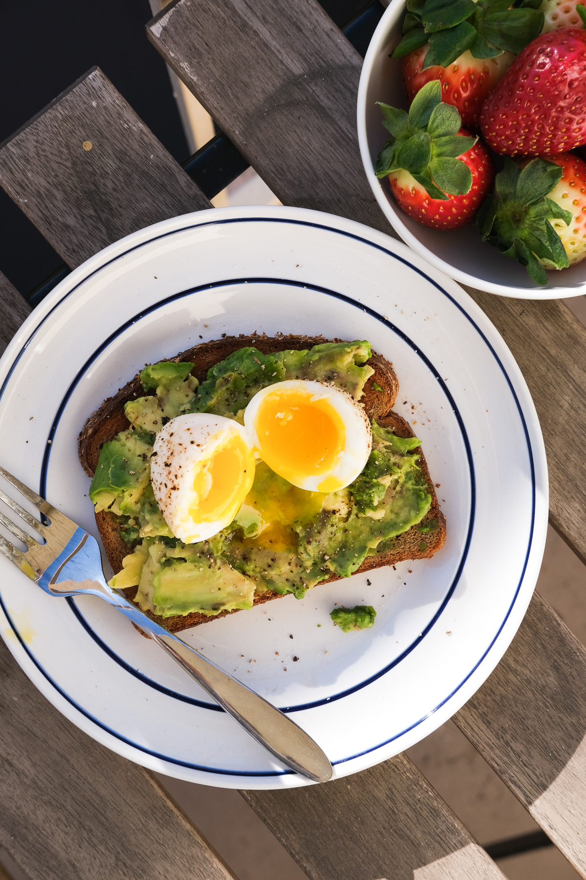 avocado toast with soft boiled eggs and a side of strawberries