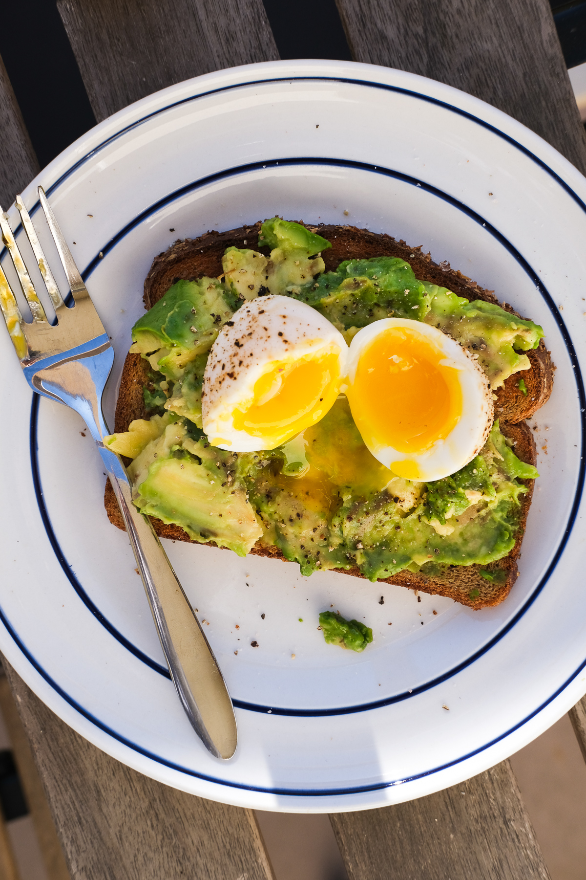 avocado toast on a plate outside with a soft boiled egg