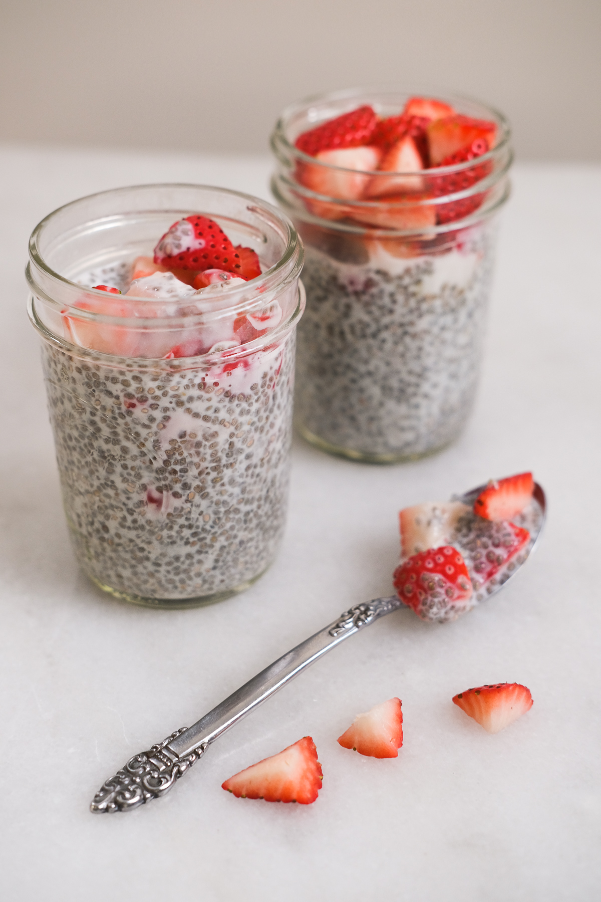 spoonful of chia seed pudding on a marble counter with mason jars