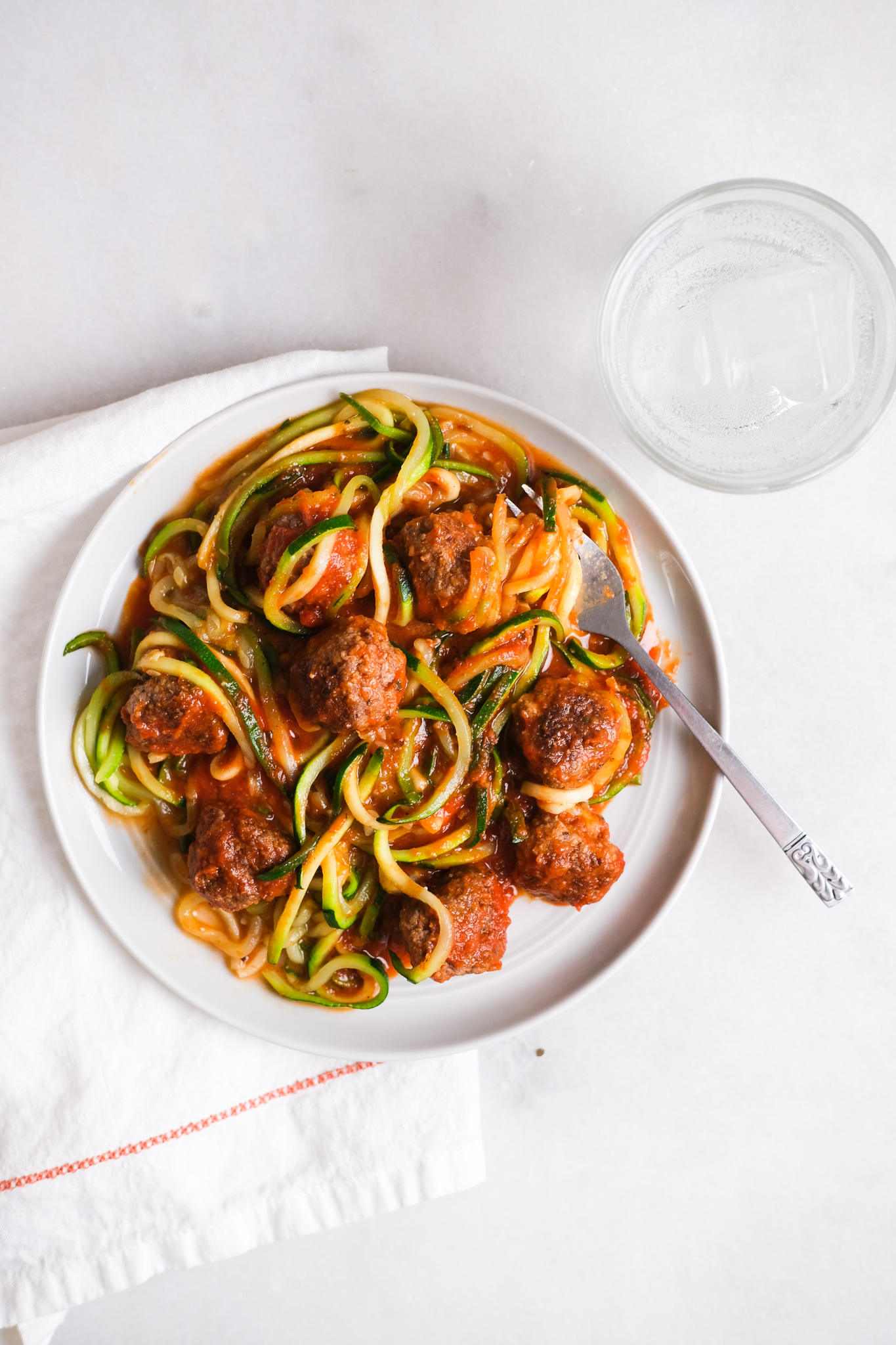 bowl of zoodles and meatballs on a marble counter