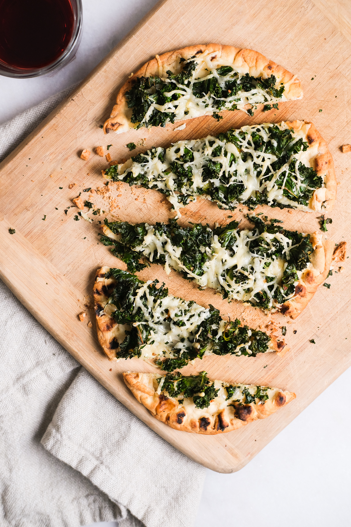 kale parmesan flatbread pizza cut up on a cutting board