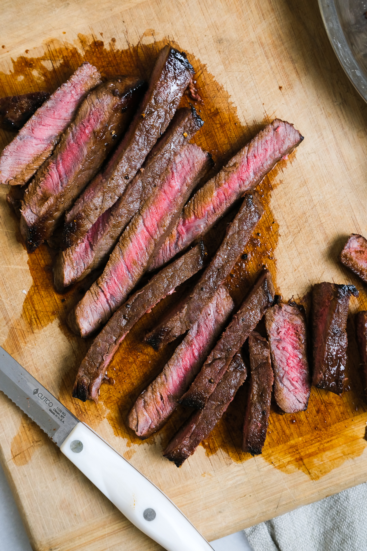 close up of london broil sliced up on a cutting board