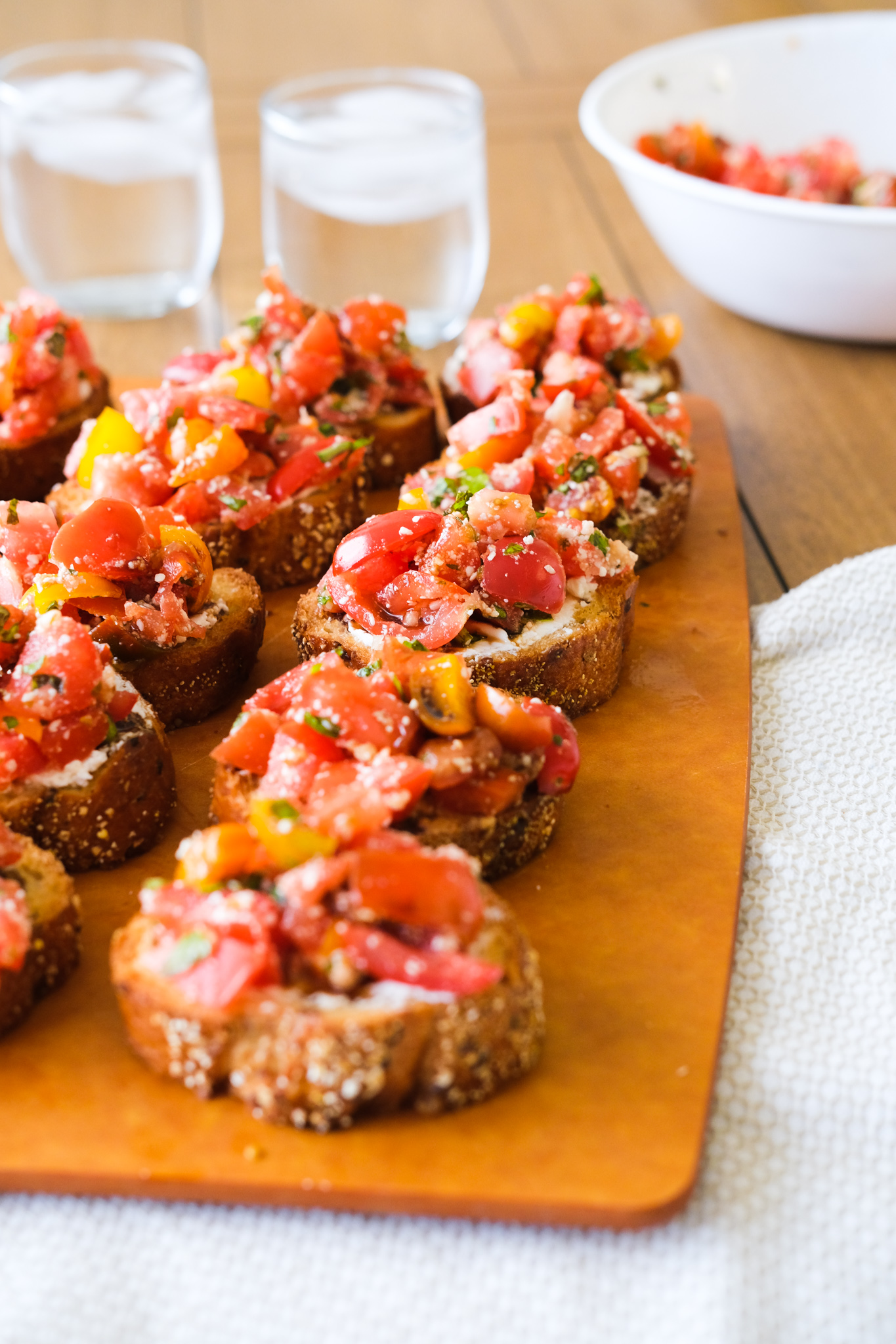 bruschetta on a cutting board with glasses of water