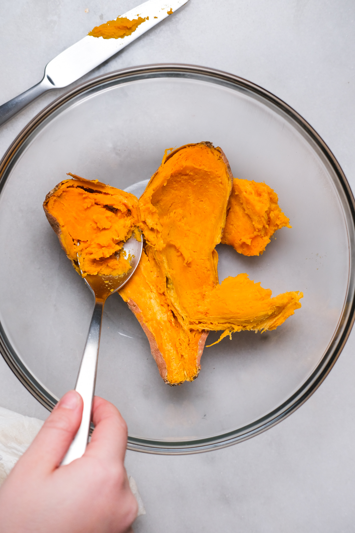scooping out a cooked sweet potato