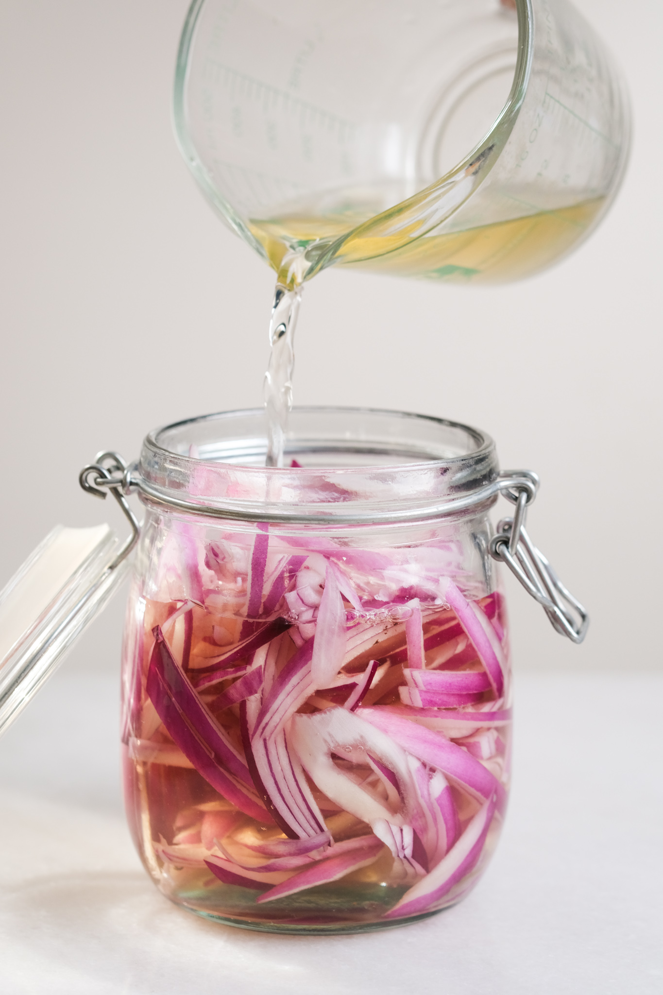 pouring vinegar base into the mason jar for pickling red onions