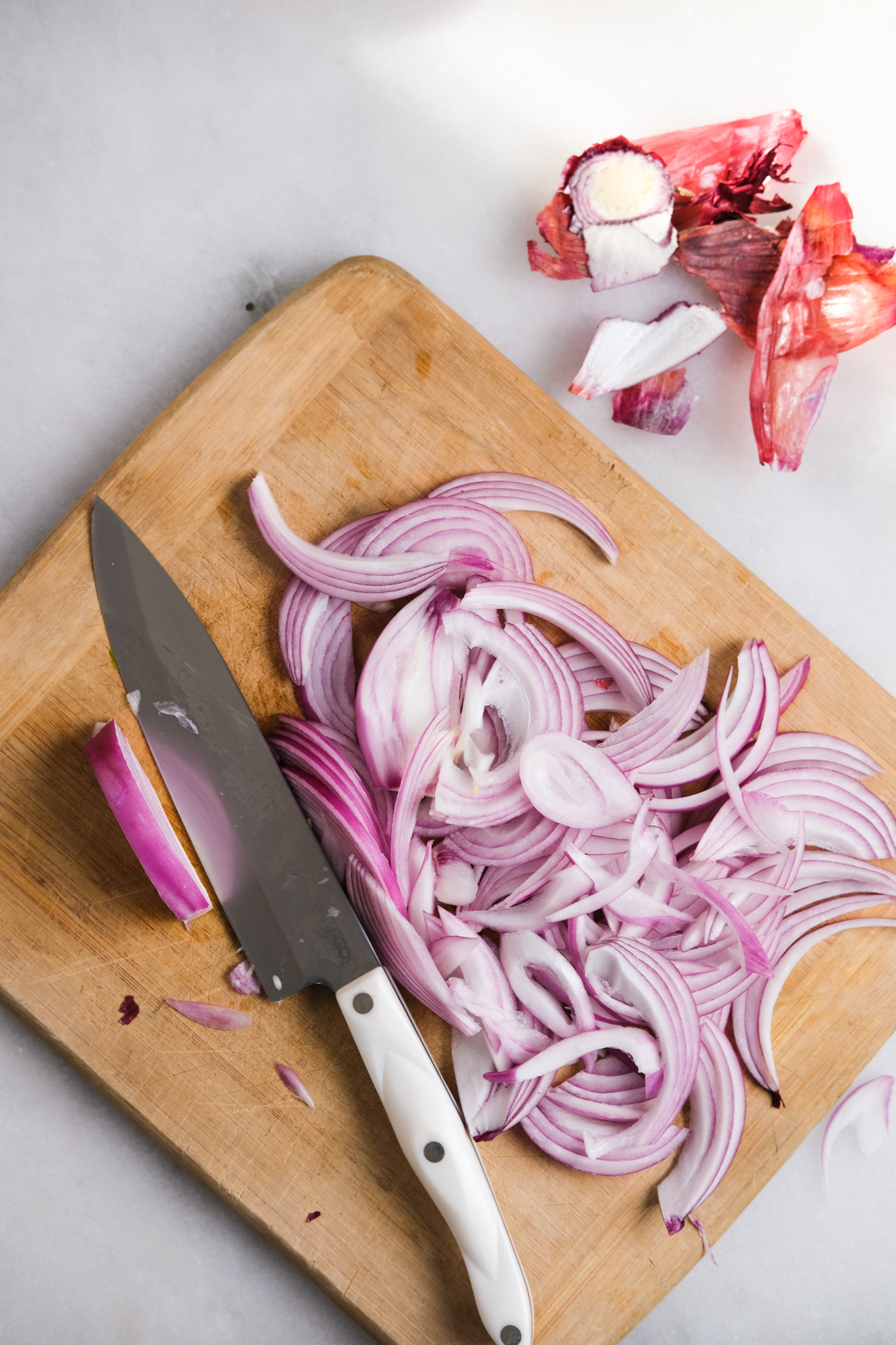 slicing red onions on a cutting board