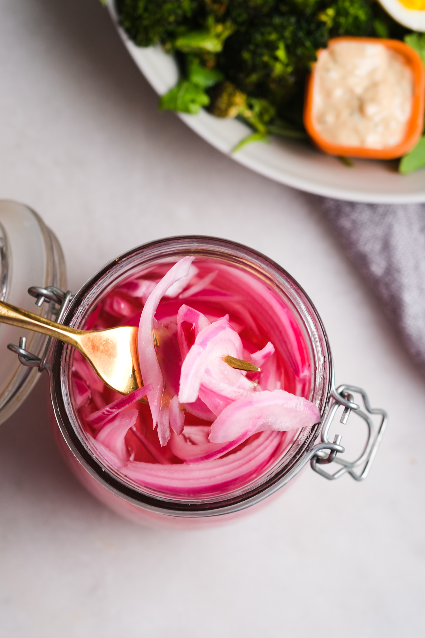picking out pickled red onions from a jar
