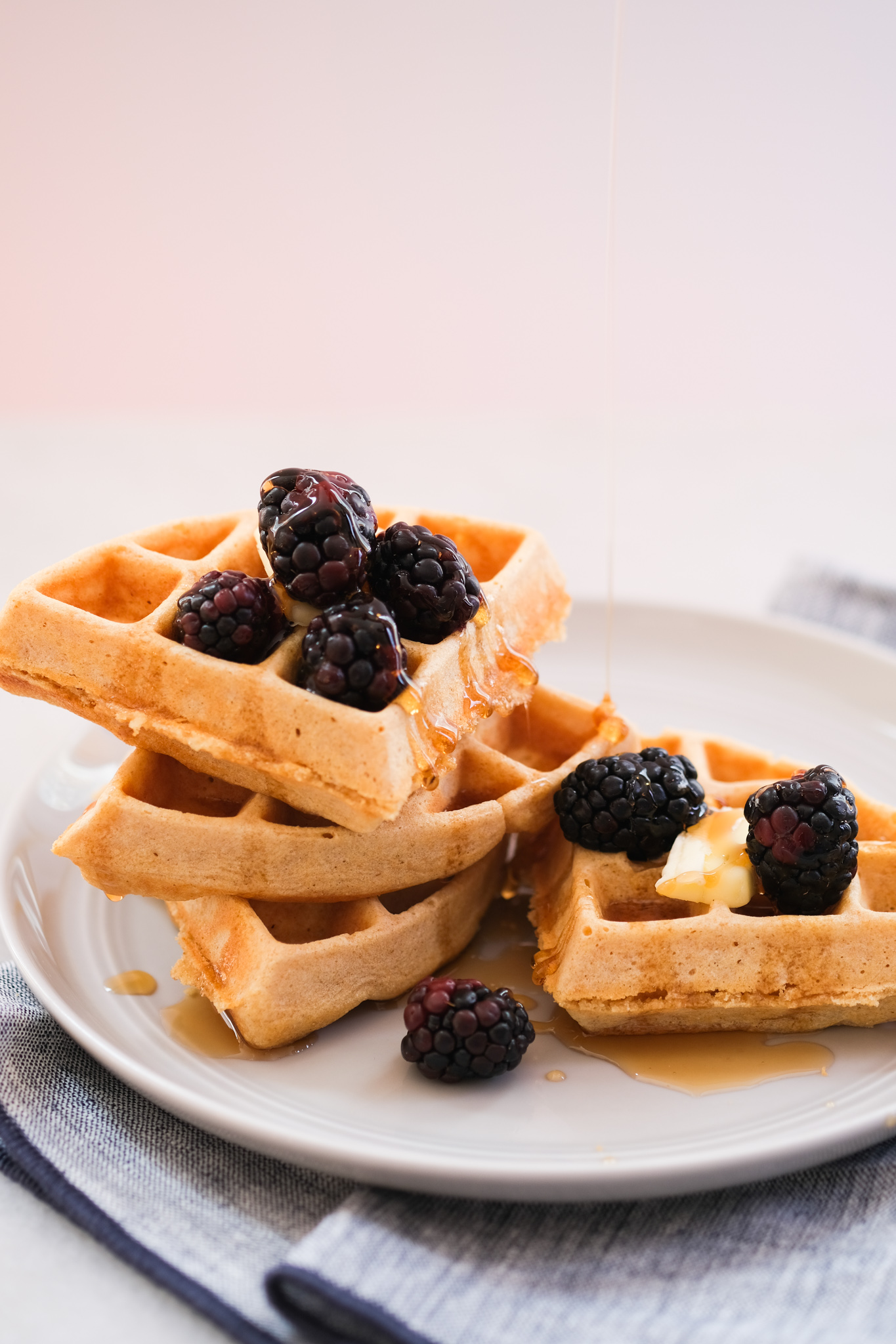 whole wheat waffles with blackberries and syrup drizzled on top