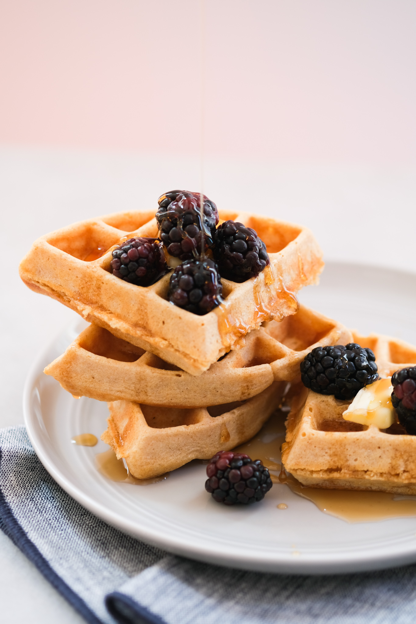 drizzling maple syrup on a berry with whole wheat waffles