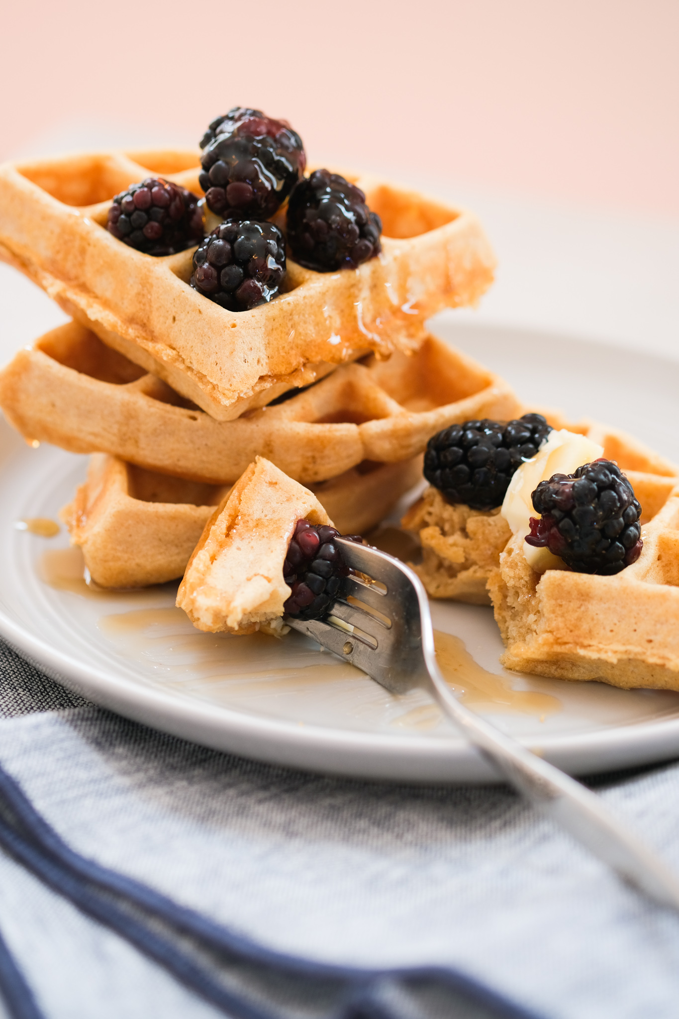 biting into a whole wheat waffle with blackberries