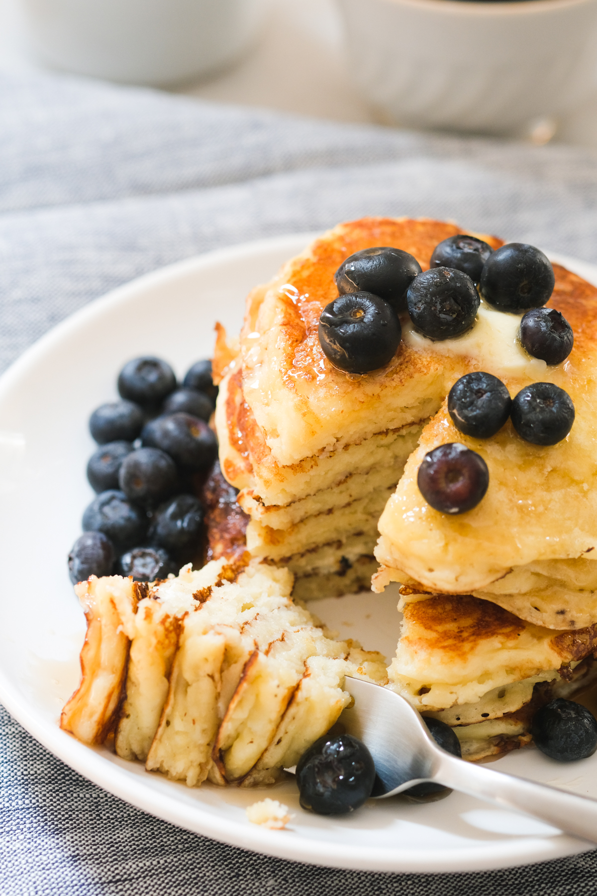 cutting into a stack of blueberry lemon ricotta pancakes