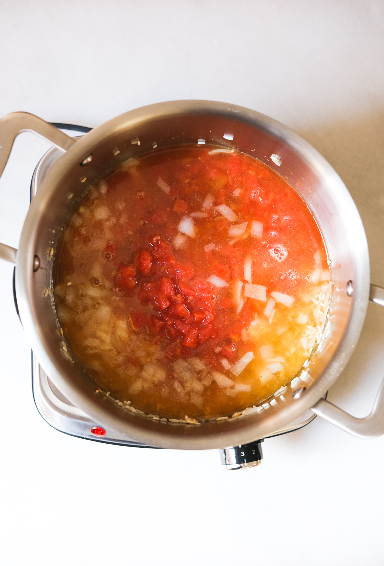 Pouring in broth and diced tomatoes for Mexican rice