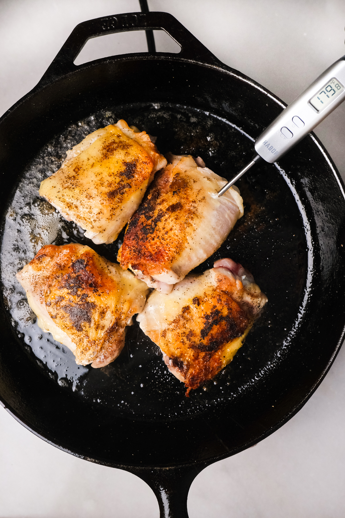 checking temperature of chicken thighs in a skillet
