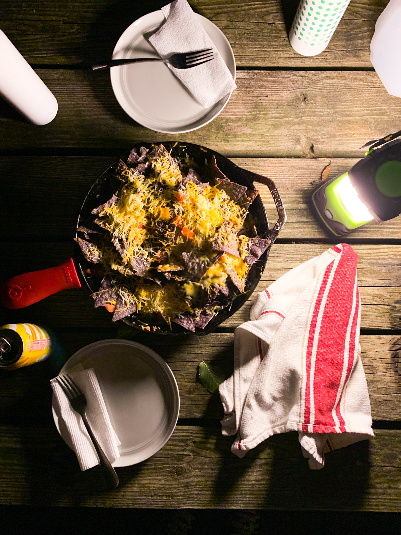 nachos in a cast iron skillet at night while camping on a picnic table