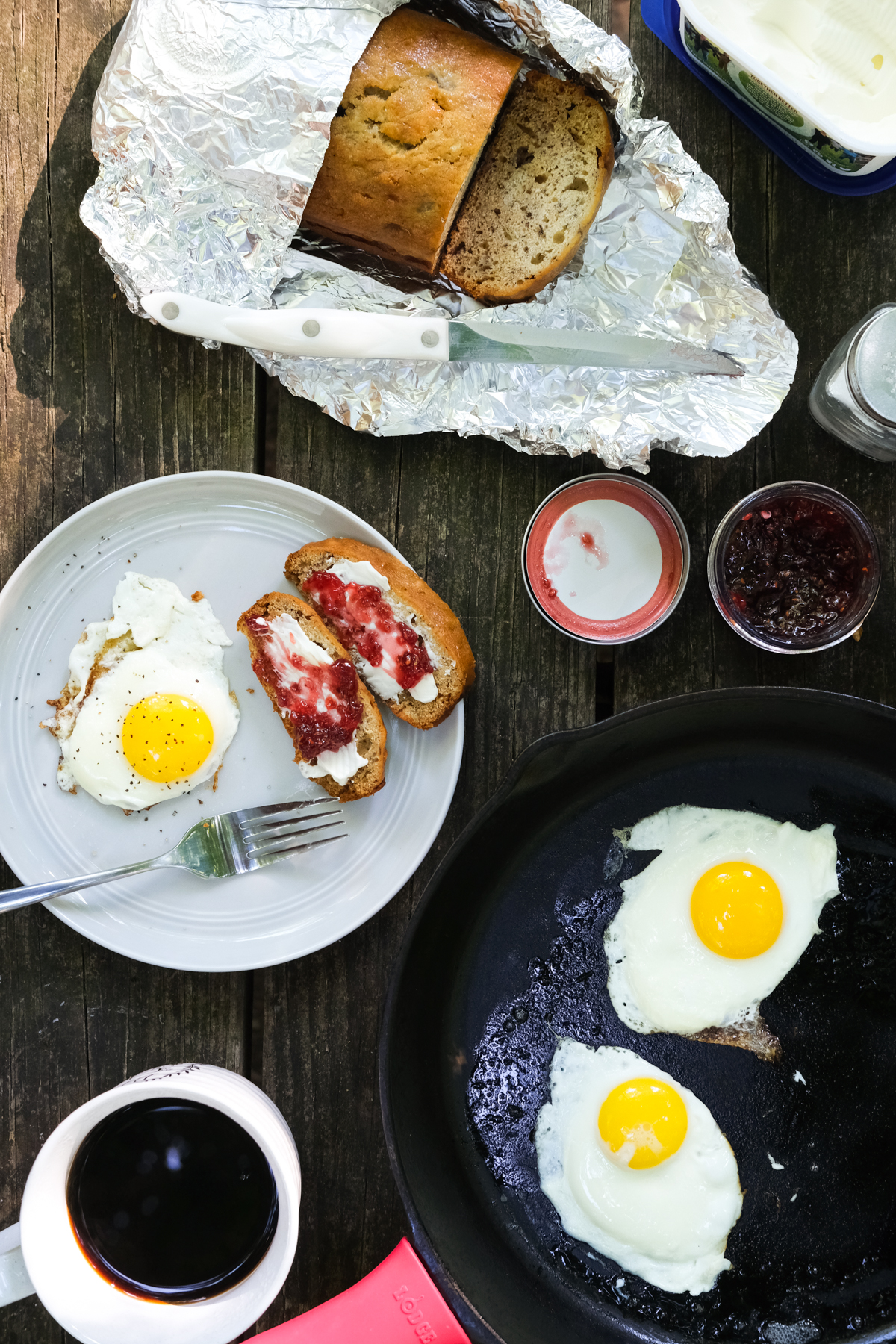 eggs and banana bread with jam and coffee on a picnic table