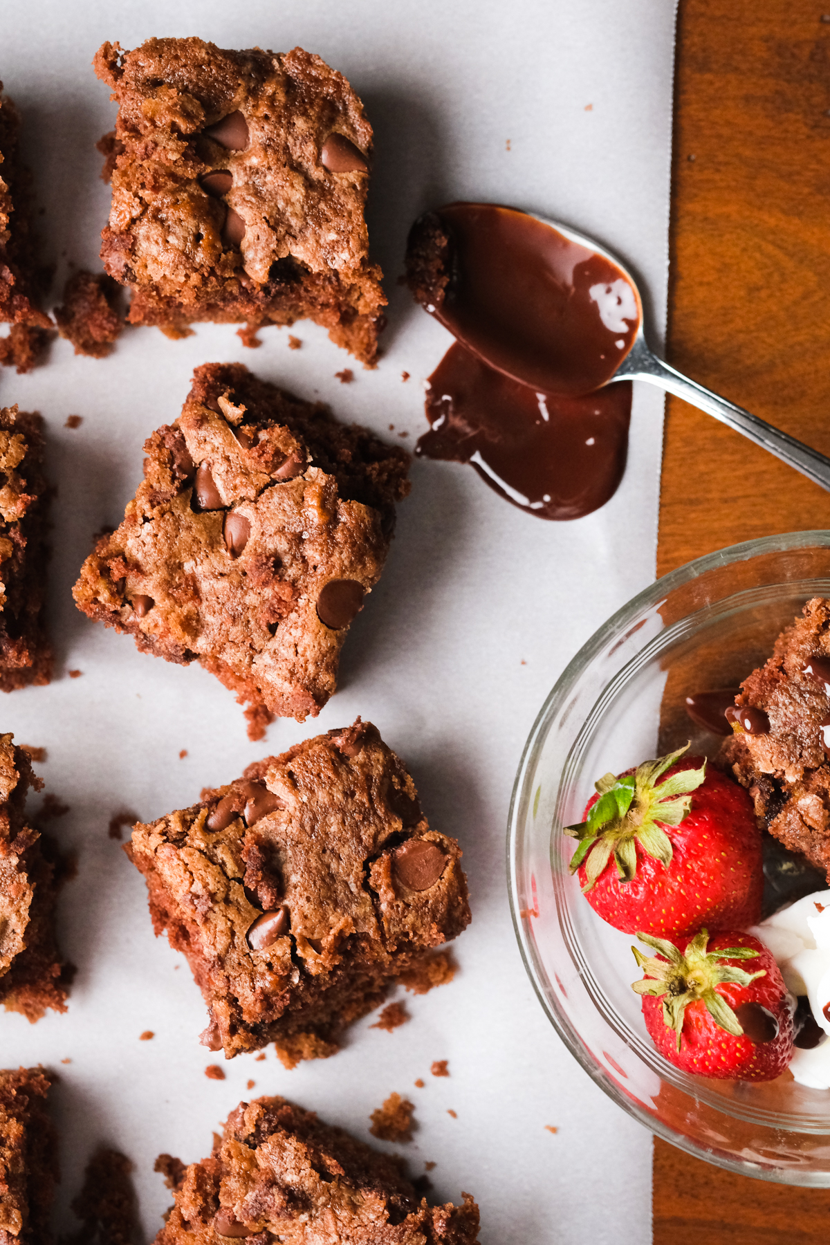 zucchini brownies with melted chocolate and a bowl with strawberries