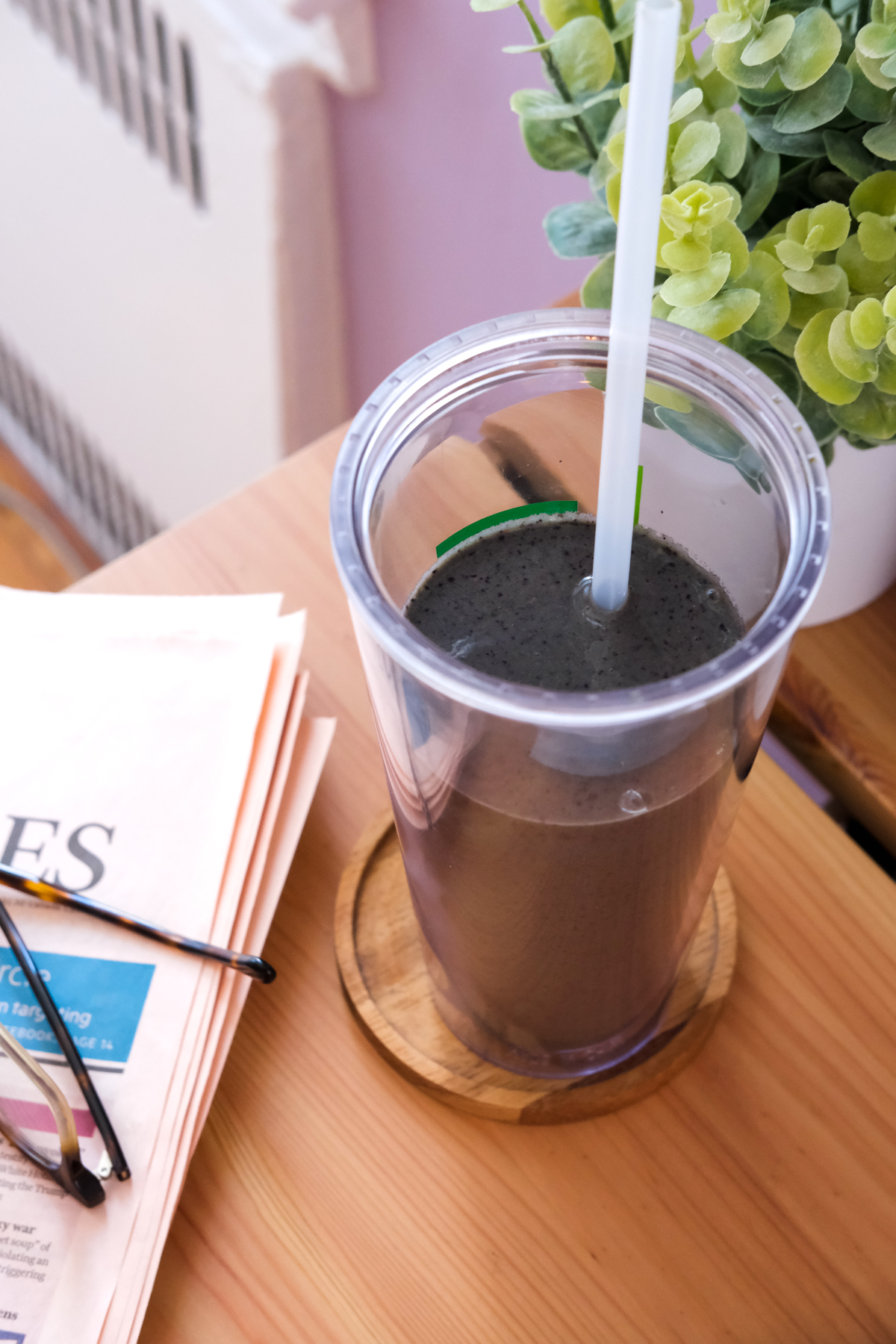 blueberry superfood smoothie on a desk with a newspaper and glasses