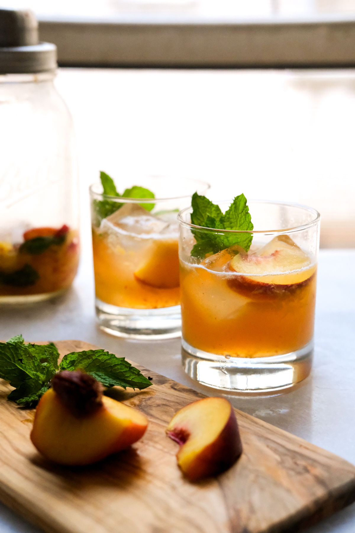 peach bourbon smash with cocktail shaker and peach slices