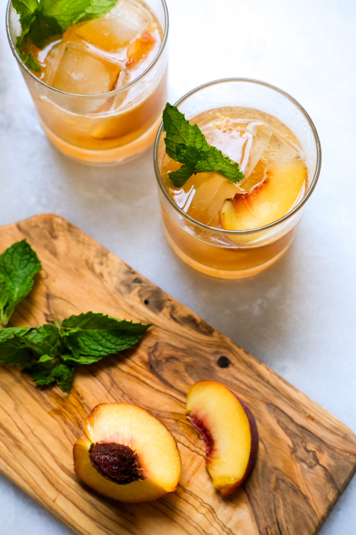 peach bourbon smash cocktails with peach slices and mint garnish