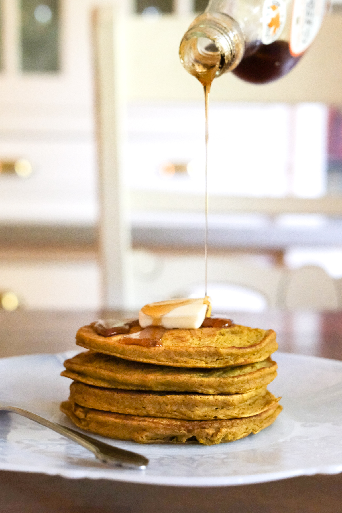 pouring syrup on a stack of pumpkin pancakes