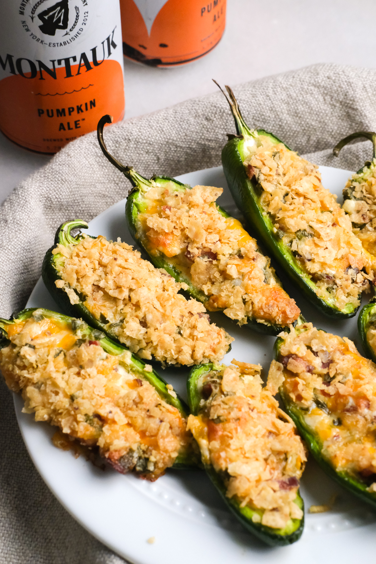 baked jalapeno poppers on a plate with cans of beer