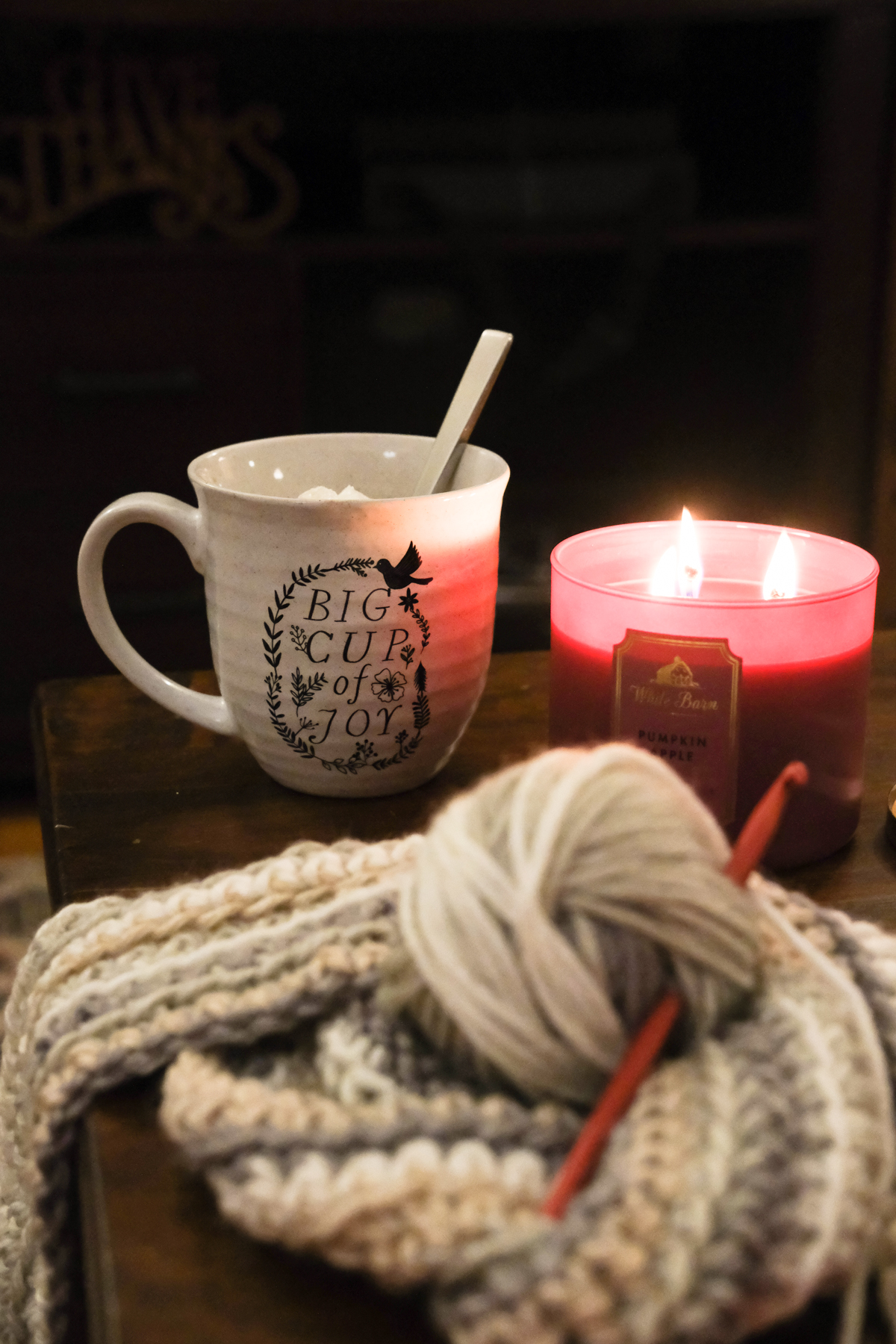 mug candle and crochet project on a coffee table