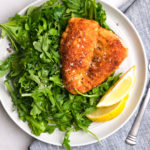 breaded chicken on a bed of arugula with lemon slices