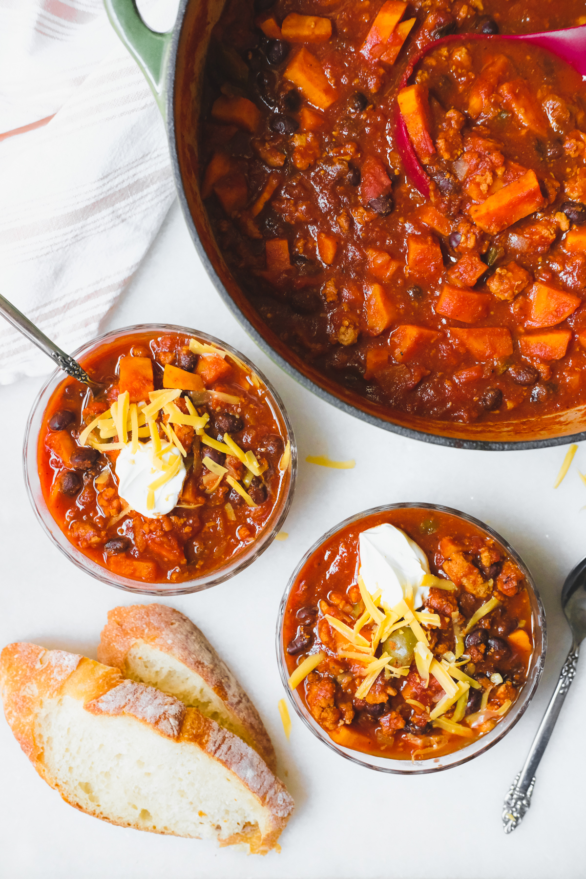 scooping bowls of sweet potato turkey chili with sour cream and cheese on top
