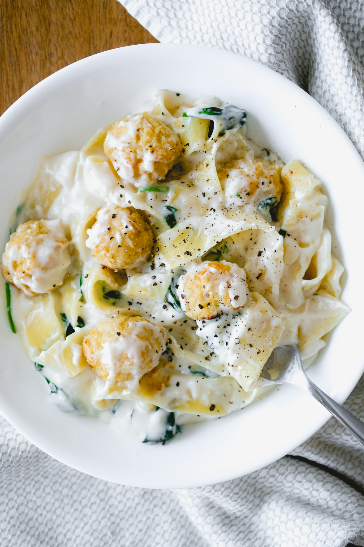 a bowl of chicken meatballs with cheesy spinach pappardelle