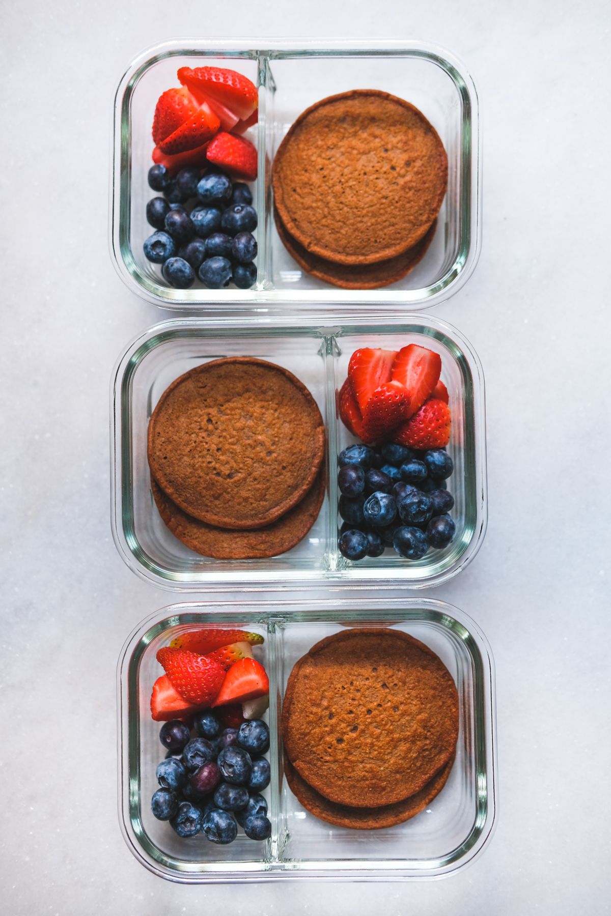 chocolate protein pancakes in meal prep containers with berries