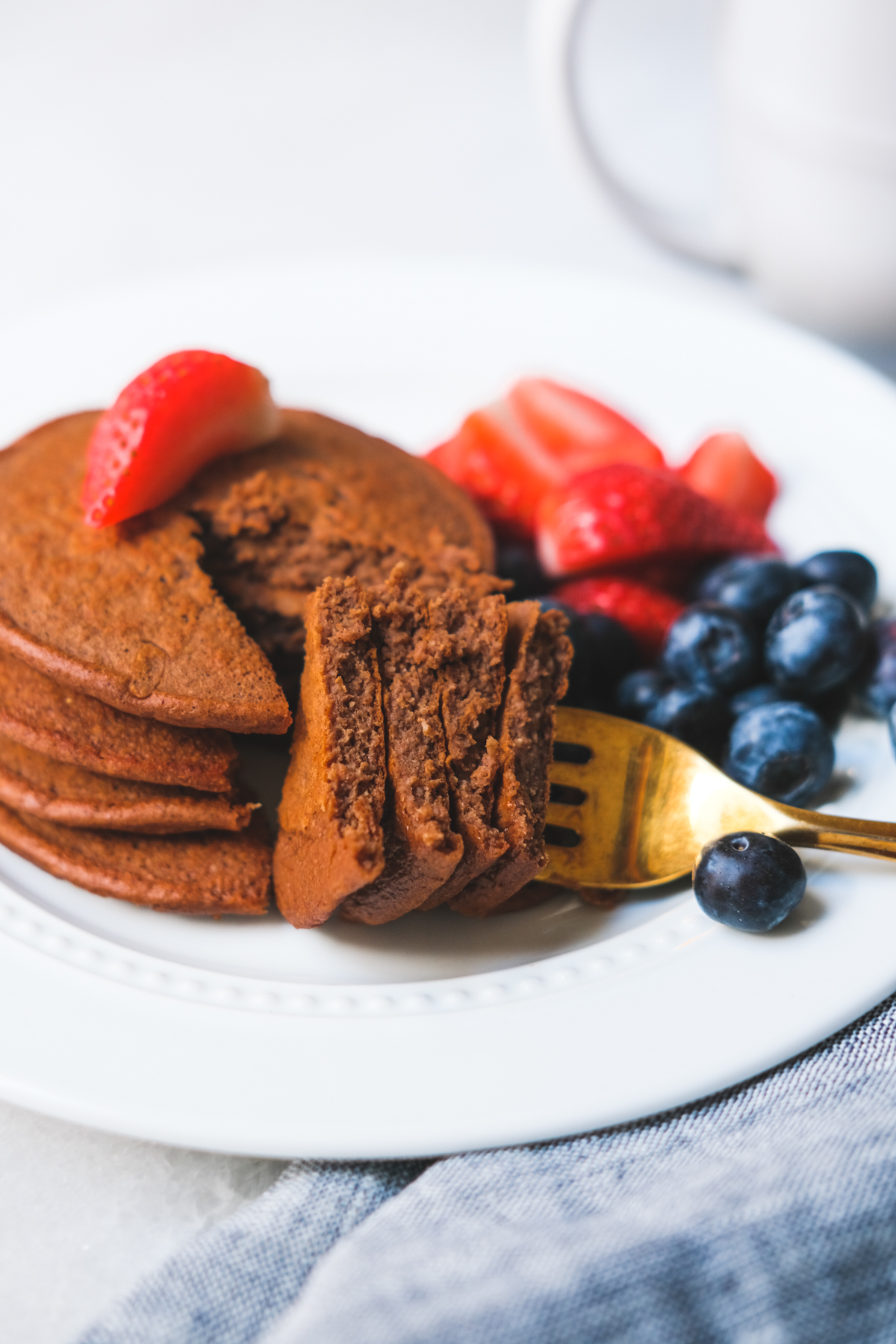 forkful of chocolate protein pancakes with berries on a plate