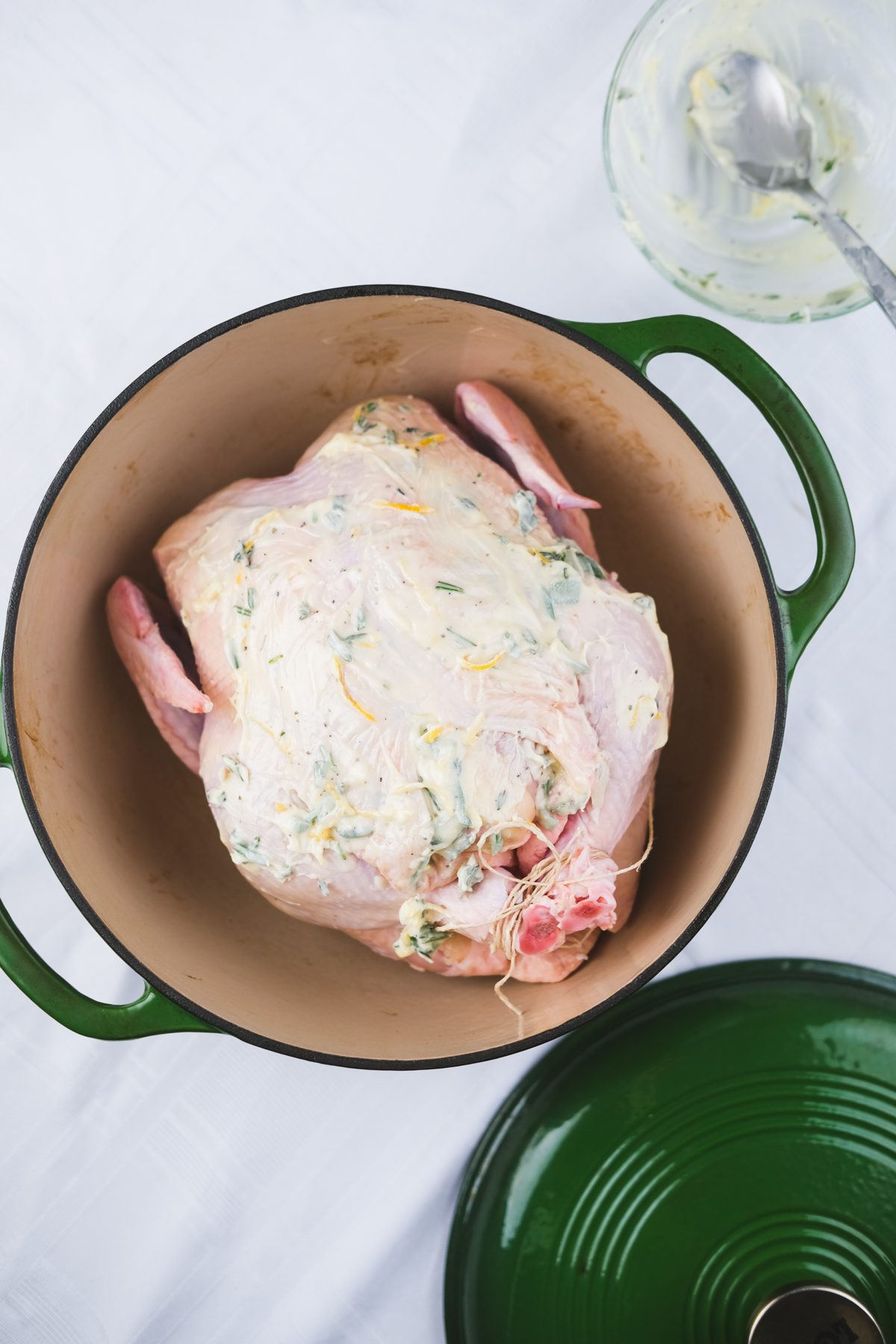 prepping a dutch oven roast chicken with butter and herbs before going in the oven