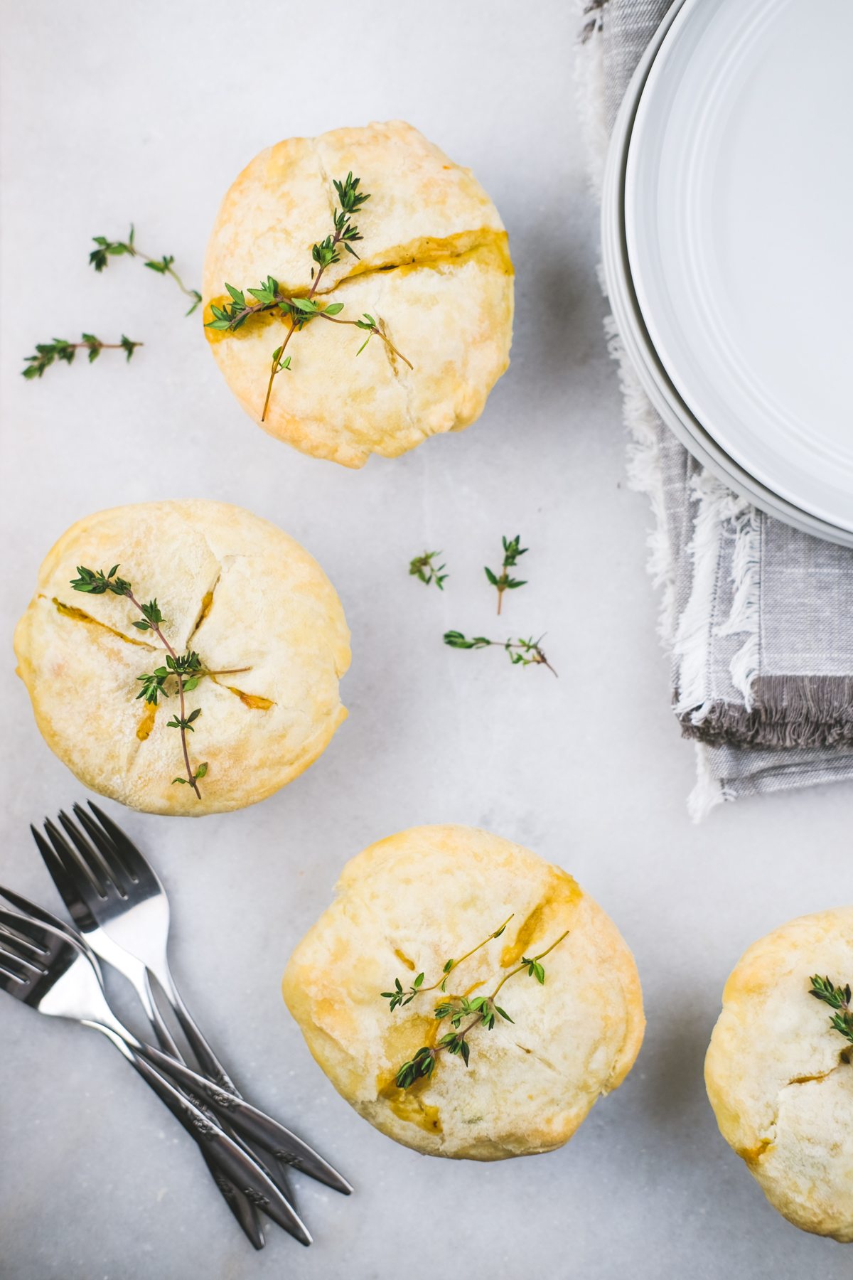 mini chicken pot pies in ramekins scattered on a table with thyme garnished on top