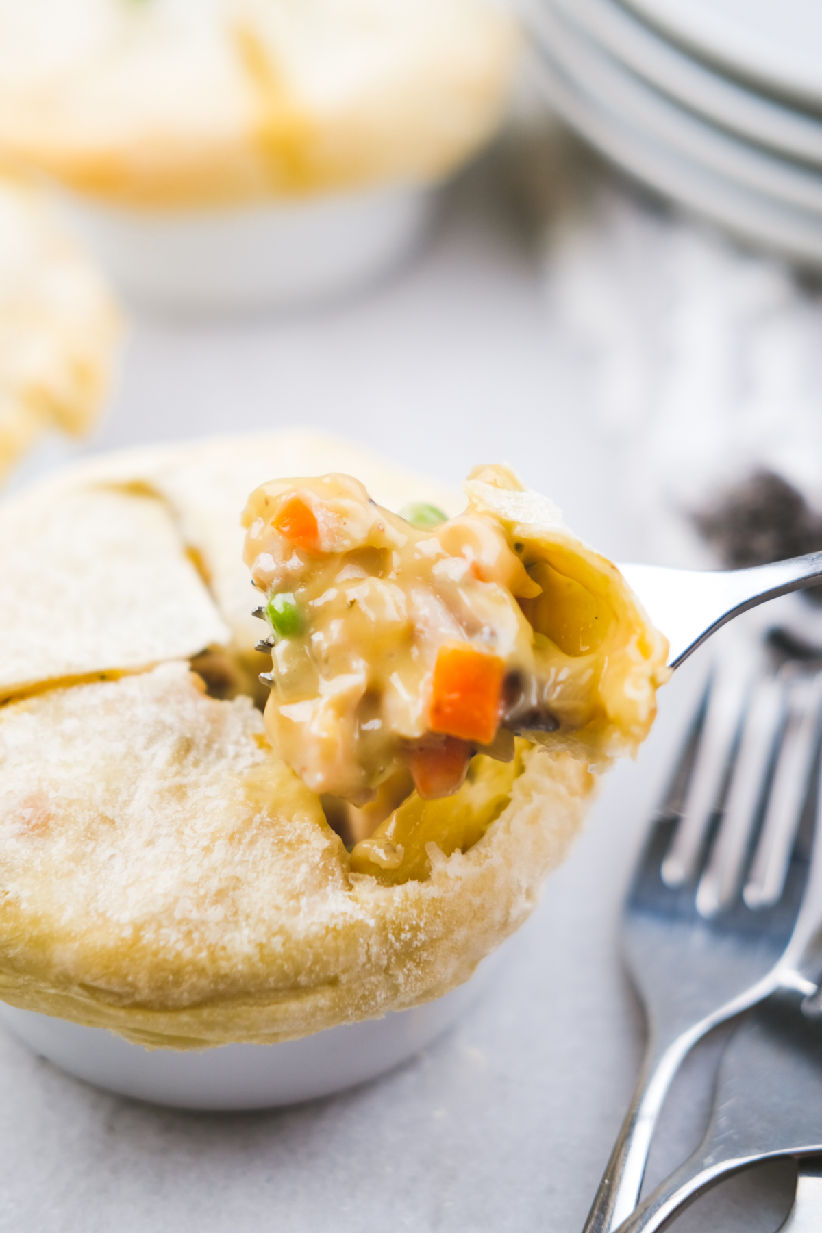 forkful of mini chicken pot pies in ramekins with creamy center