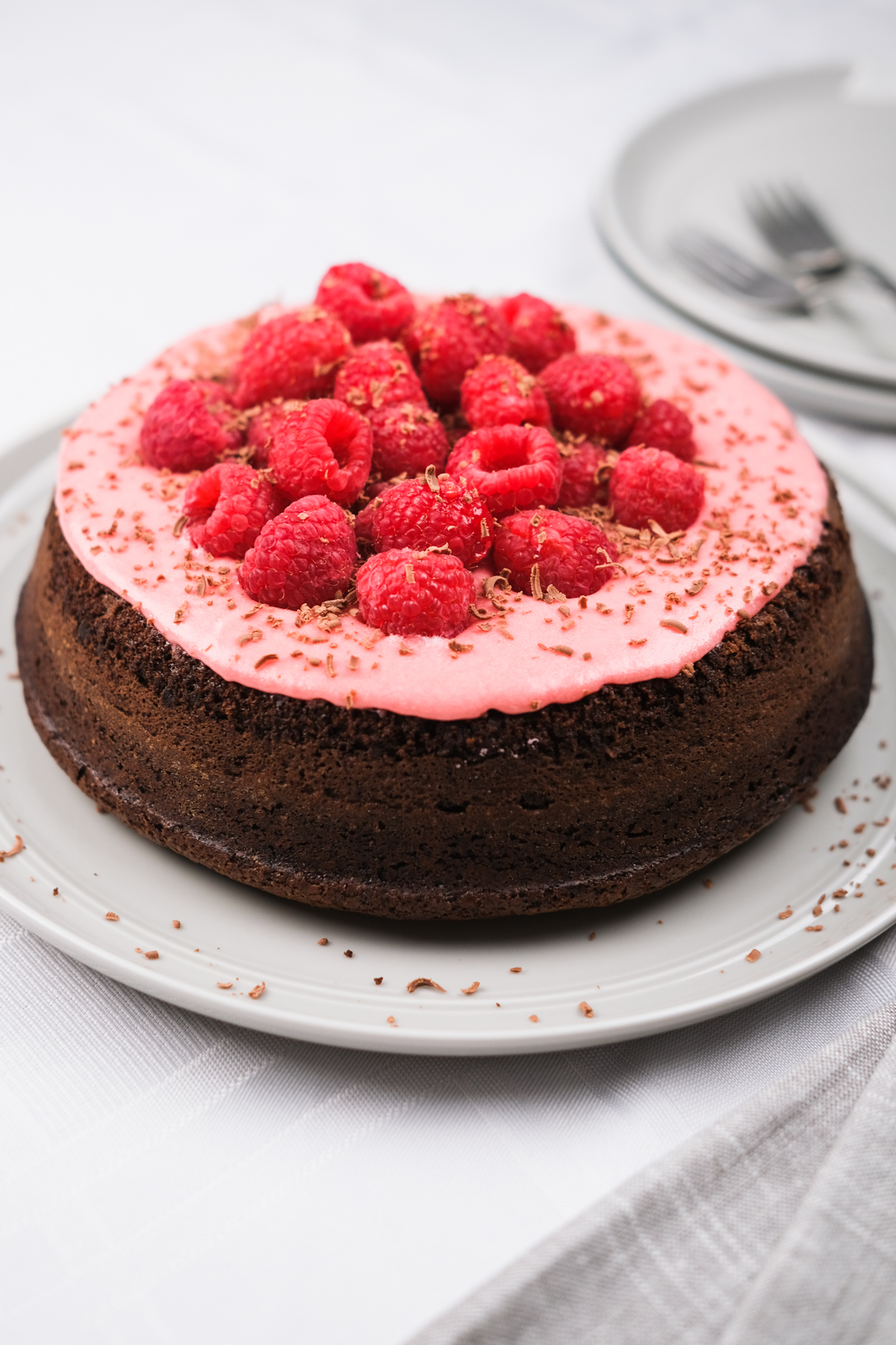 single layer chocolate cake with pink raspberry frosting and fresh berries