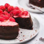 slicing up a chocolate raspberry cake with fresh berries and chocolate shavings
