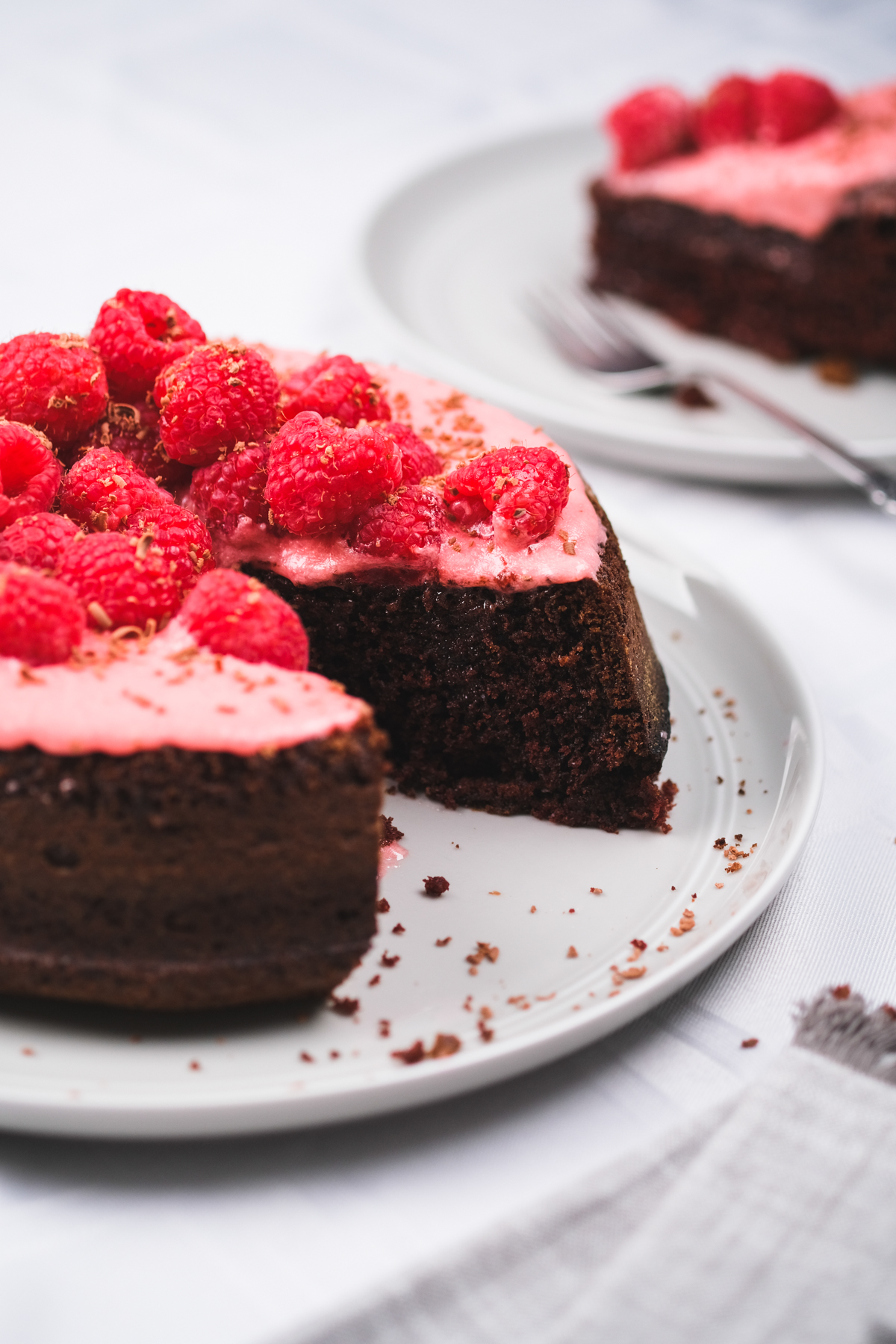 slicing up a chocolate raspberry cake with fresh berries and chocolate shavings