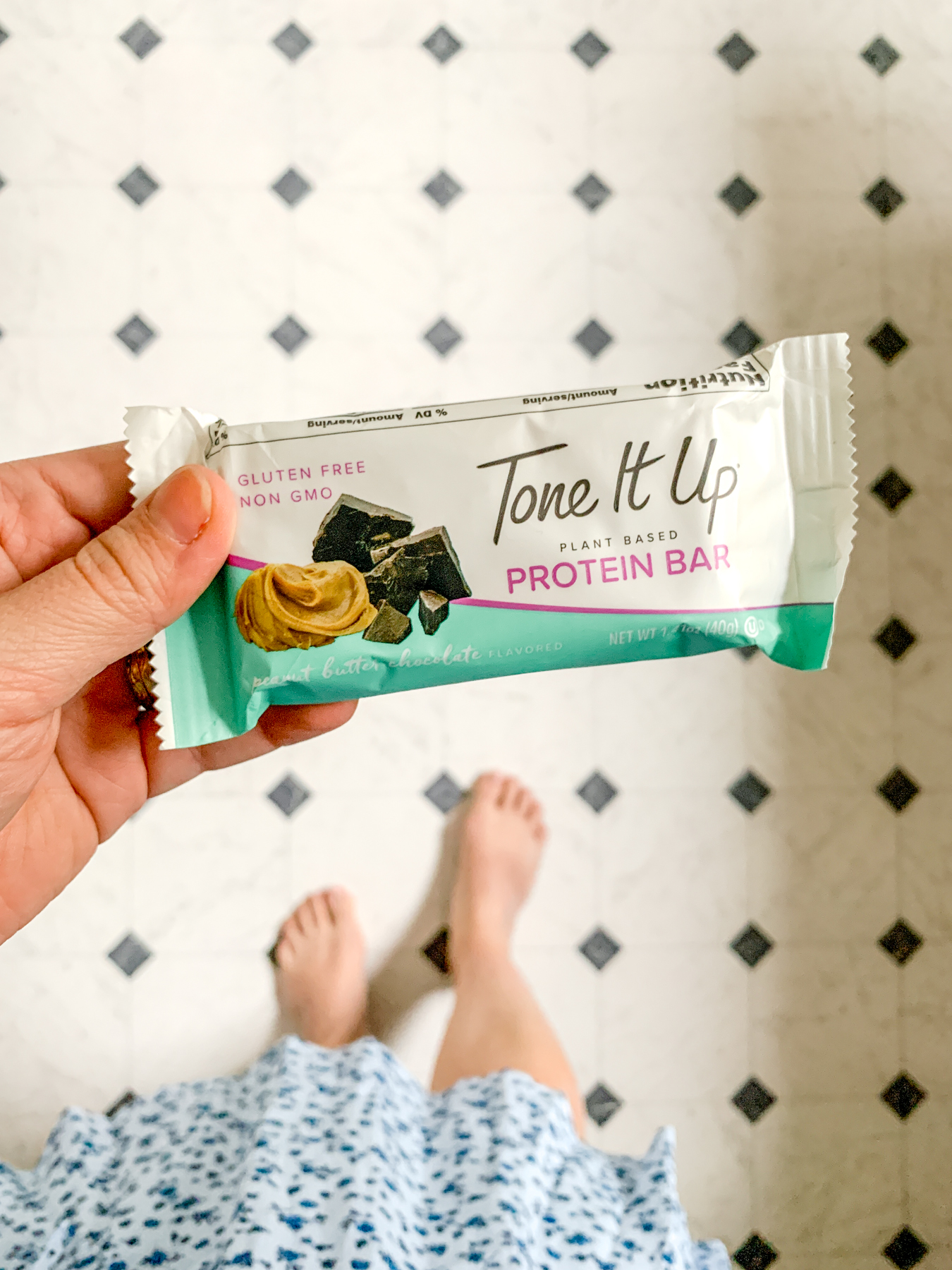 holding a tone it up chocolate peanut butter protein bar
