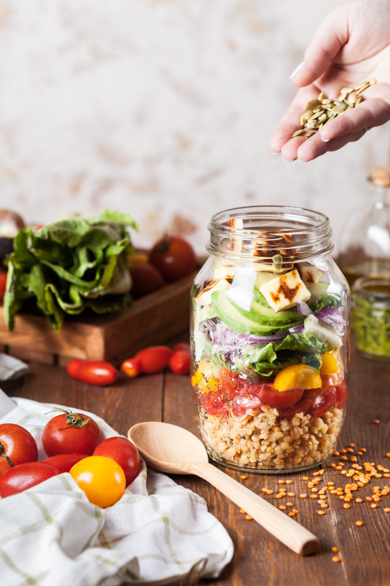 filling a mason jar with a healthy lunch