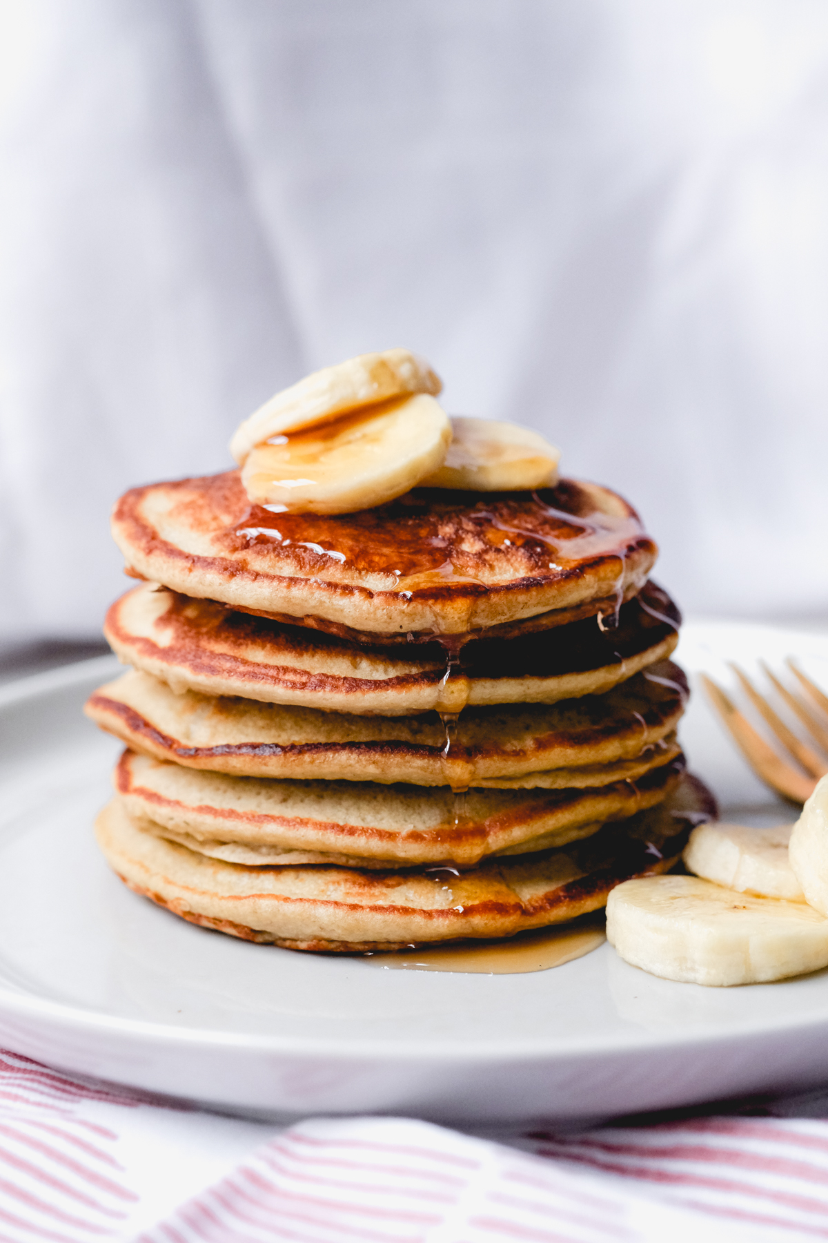 single stack of banana oatmeal pancakes with banana slices and syrup